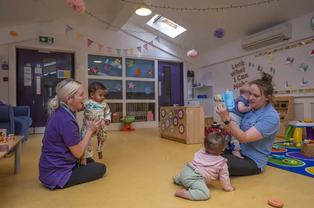 two puddleducks staff assist young children- holding and playing with them